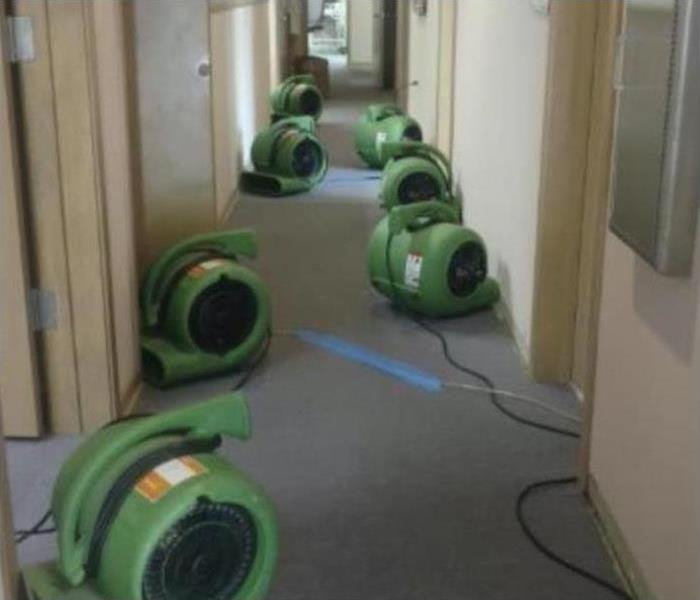Seven air movers placed in the hallway of a building