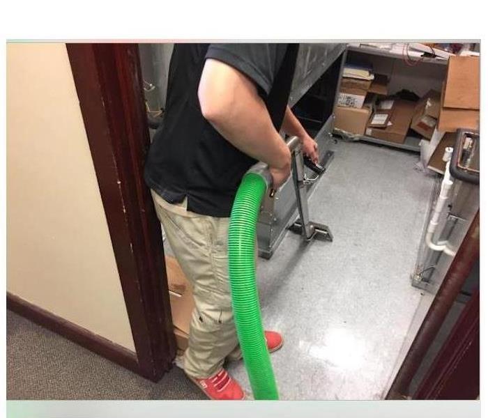 technician extracting water with vacuum in an office building.